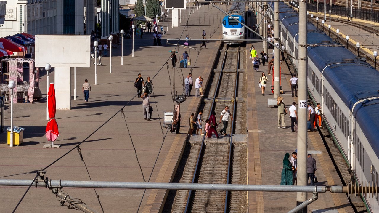 Passengers on the platform as a train arrives at Bukhara Railway Station in Kogon